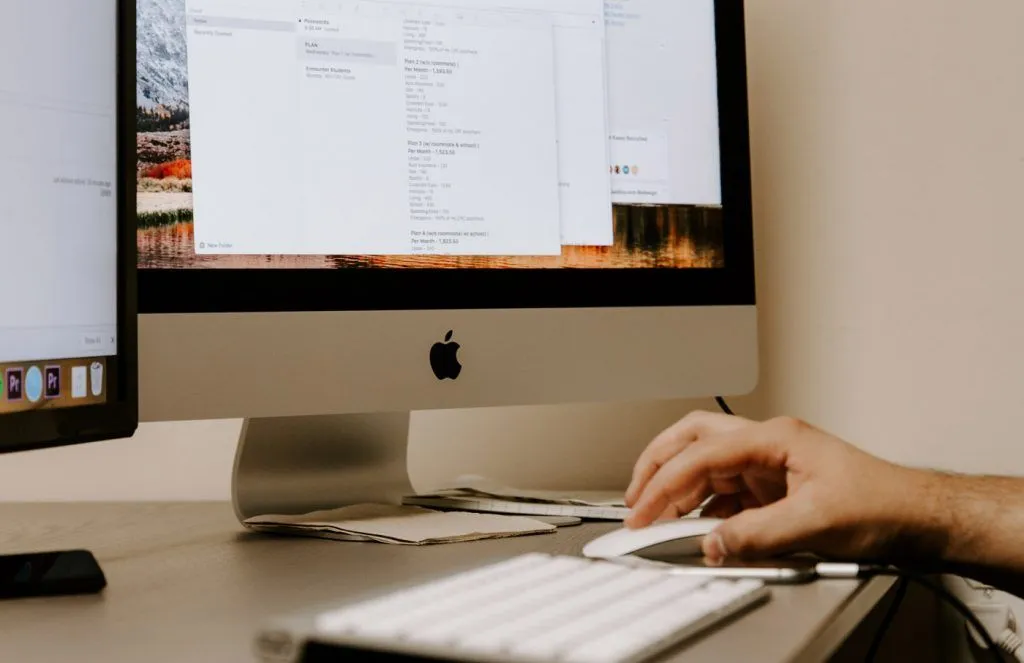 man holding mouse in front of an imac